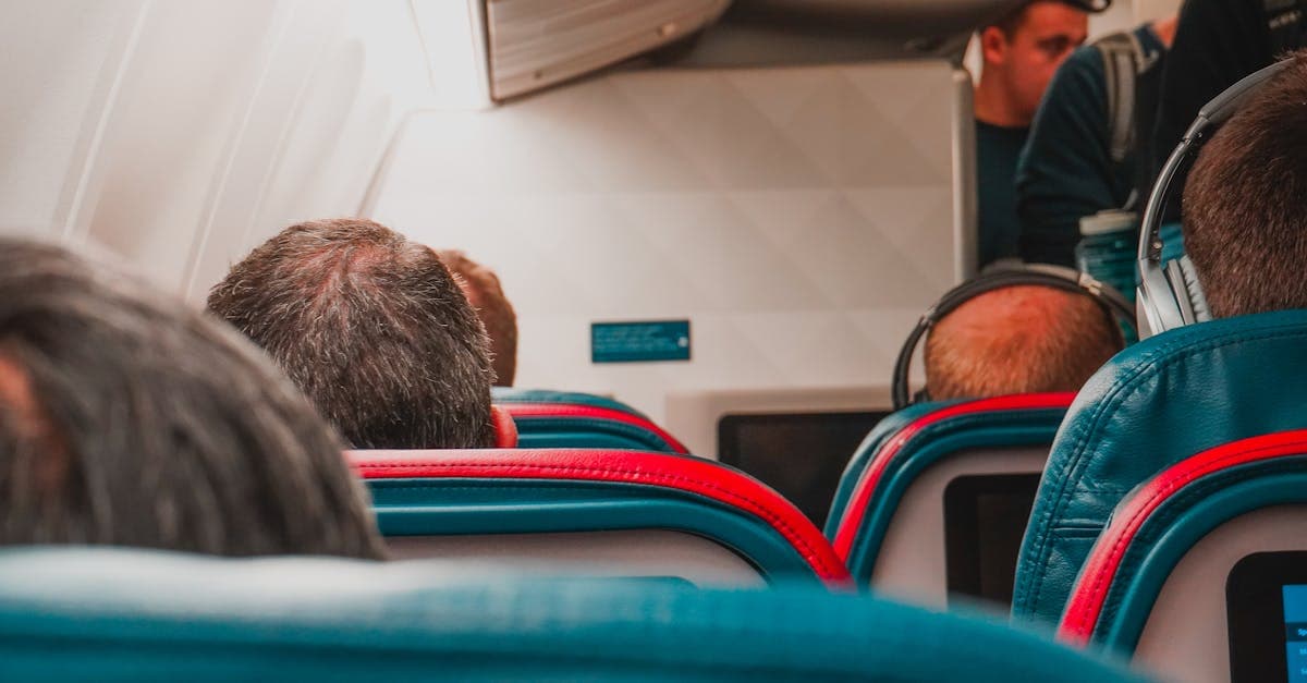 Rows of economy seats in an airplane cabin, where a personal item stows in the footwell.